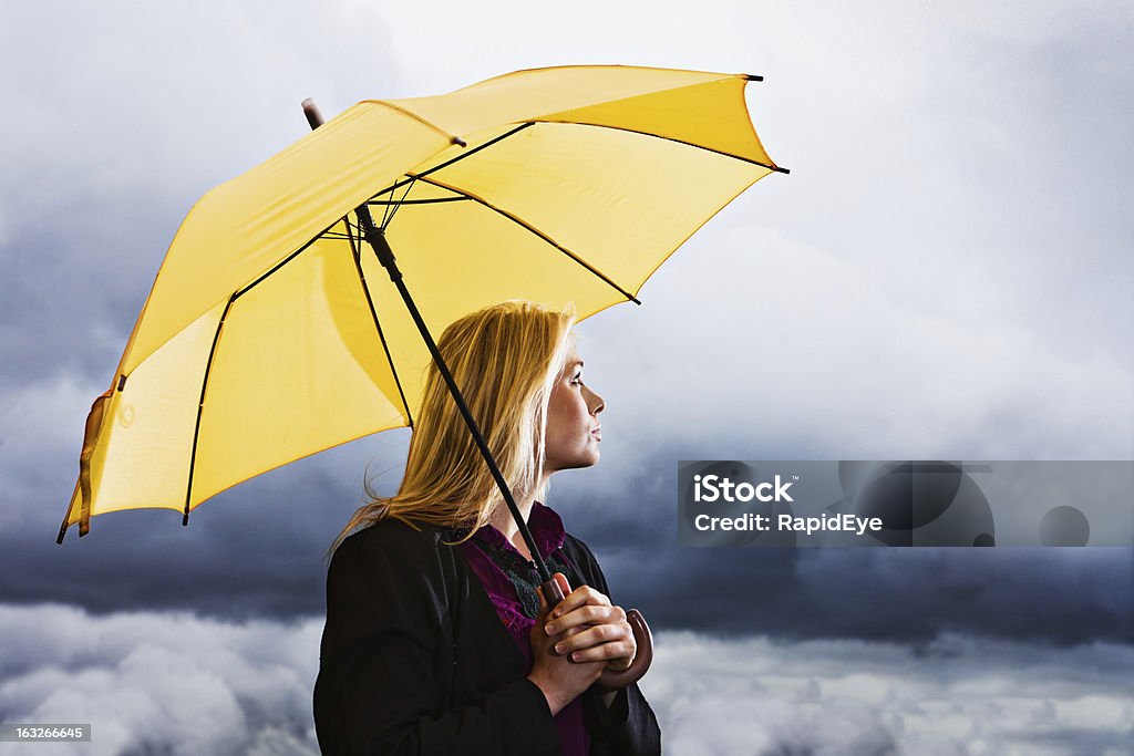 Le tempeste: wistful bionda con ombrelloni gialli attende il temporale - Foto stock royalty-free di Donne