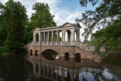 Marble bridge on the shore of a Large pond in the Catherine Park in Tsarskoye Selo on a sunny summer day, Pushkin, St. Petersburg, Russia