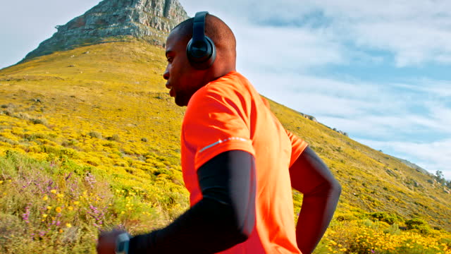 Mountain, music headphones or black man running, listen to podcast and outdoor nature exercise, training or fitness. Streaming workout podcast, nature or African male runner or doing cardio challenge