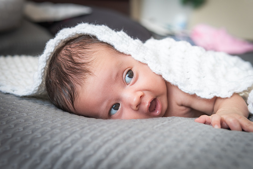 baby with eyes and mouth open lying on the bed. High quality photo