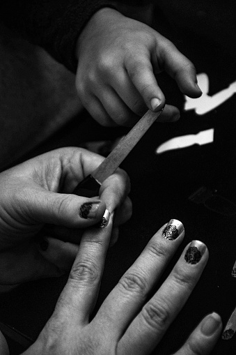 little girl helping her mother put on a nail sticker