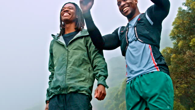 Help, helping hand and success by men athletes celebrating after hiking, fitness or outdoor workout in nature. Mountain, trekking and teamwork by people or friends doing exercise as a team together