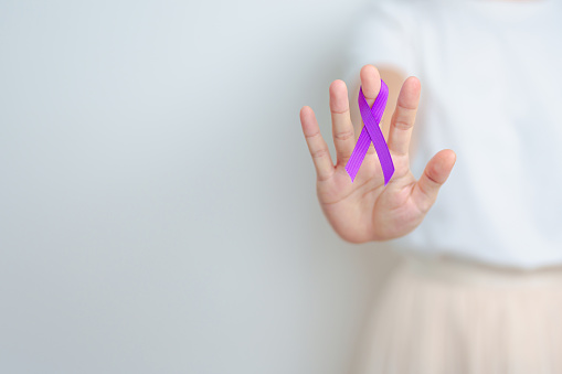 Woman holding purple Ribbon for Violence, Pancreatic, Esophageal, Testicular cancer, Alzheimer, epilepsy, lupus, Sarcoidosis and Fibromyalgia. Awareness month and World cancer day concept