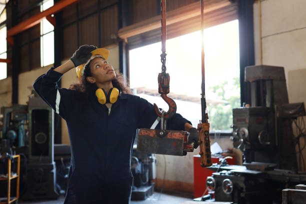 istock Technician engineer or worker woman in protective uniform with safety hardhat standing and maintenance operation or checking overhead crane remote control at heavy industry manufacturing factory 1632782728