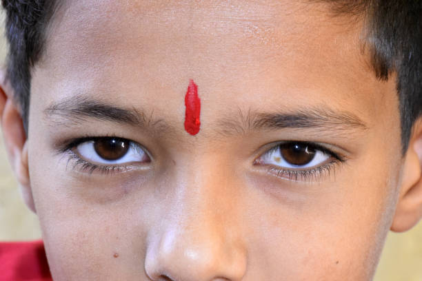 The Indian rural child with a tilak is looking at the camera.