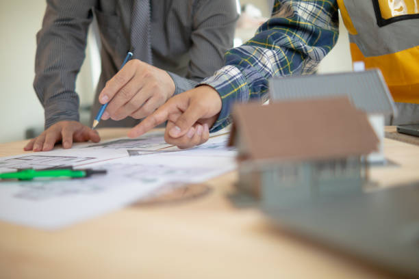 istock Construction engineers discuss and exchange ideas with architects to improve house plans to meet customer needs. A concept for exchange of design ideas between construction engineers and architects. 1632890494