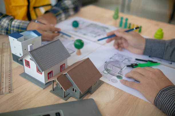 istock Construction engineers discuss and exchange ideas with architects to improve house plans to meet customer needs. A concept for exchange of design ideas between construction engineers and architects. 1632890498