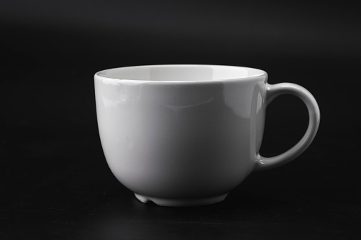 Huge white mug. White cup for tea or soup isolated on dark background with clipping path.