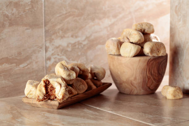 Sweet dried figs in a wooden dish on a kitchen ceramic table. Copy space.