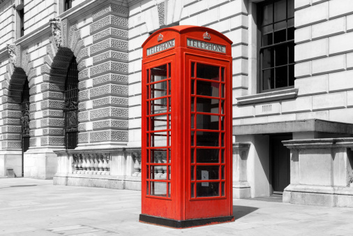 A traditional red British telephone box in London, UK. The background has been turned black and white.