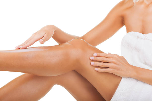 Woman applying moisturizer cream on legs stock photo