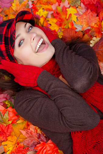 Happy Beautiful woman laying on wooden deck with fall leaves