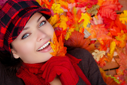 Happy Beautiful woman laying on wooden deck with fall leaves