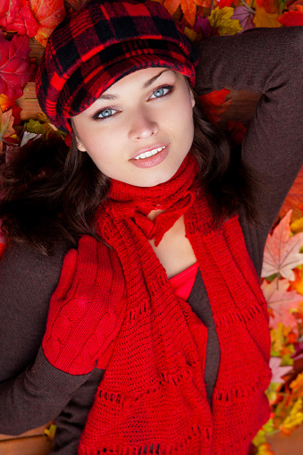 Beautiful woman laying on wooden deck with fall leaves