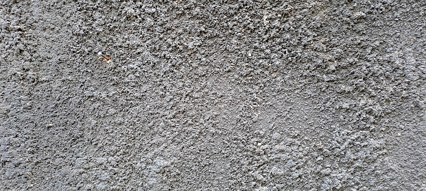The abstract texture of the gray uneven cement wall.