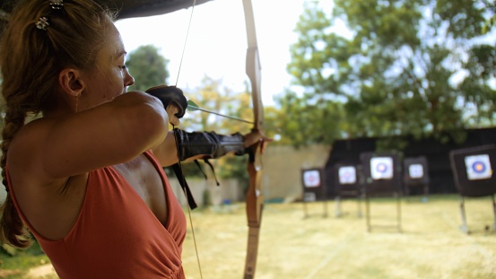 Athlete keep wooden bow. Practice and training of archery in shooting range. Sport woman in shooting range with bow. Outdoor archery training. Sportsman in shooting gallery aim an arrow to hit target