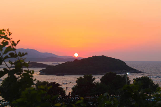 Witness the captivating beauty of a Ksamil sunset, casting its warm glow over the islands. An awe-inspiring scene of nature's artistry.