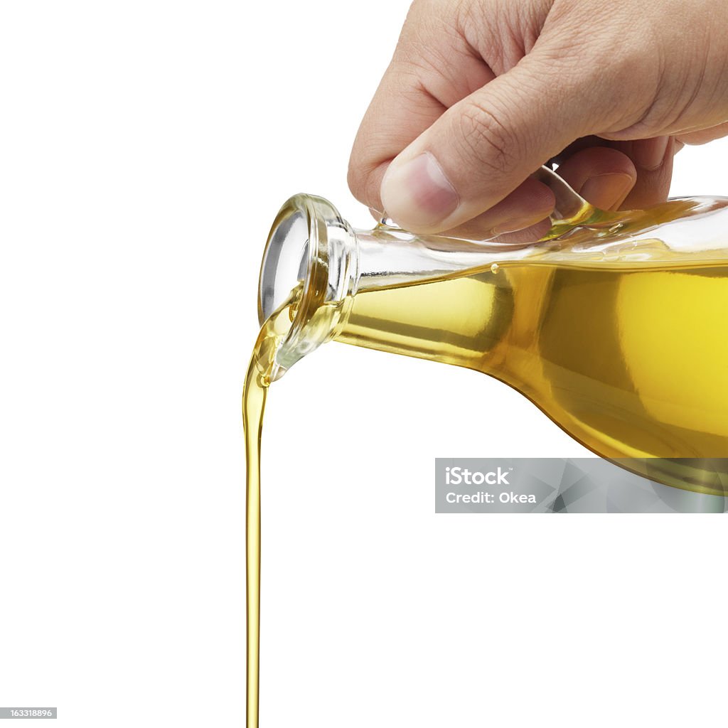 pouring oil pouring olive oil from glass bottle against white background Cooking Oil Stock Photo