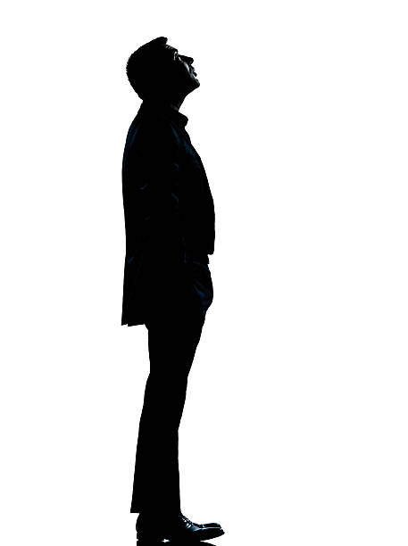 one caucasian business man silhouette standing looking up Full length in studio isolated on white background