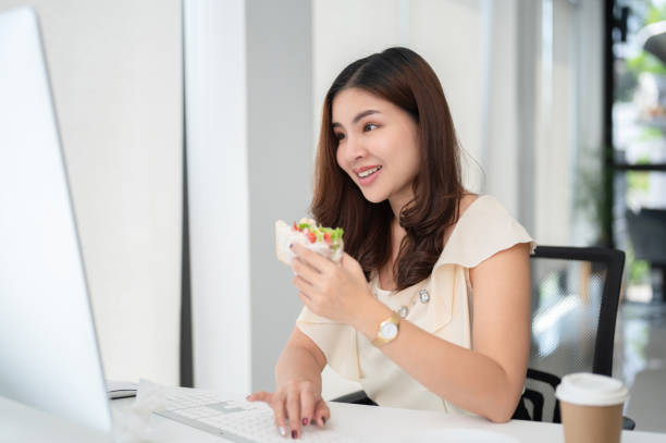 istock A beautiful, busy Asian businesswoman is eating a sandwich while working on her tasks 1633199417