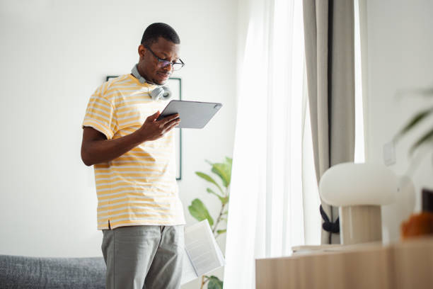 istock Cheerful African American Man Standing at Home Using a Digital Tablet for Reading and Studying 1633204946