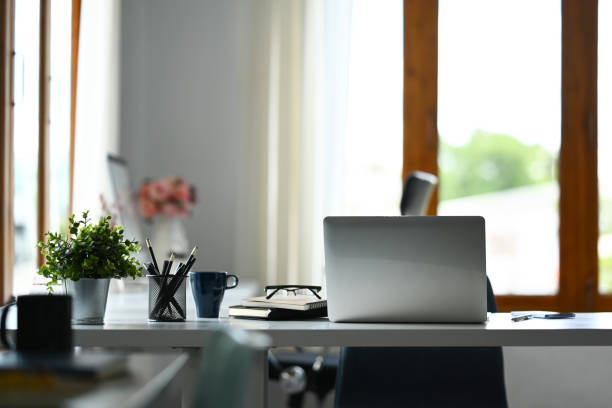 istock Comfortable workplace with laptop, coffee cup , books and potted plant on white table 1633235846