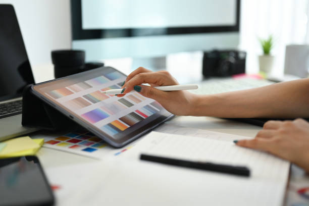 istock Closeup, select focus on woman hand choosing colors from color swatch samples chart on digital tablet 1633236378