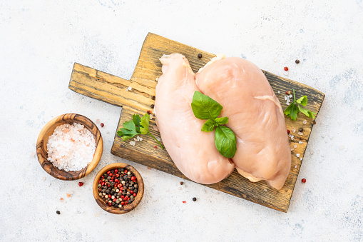 Chicken fillet, raw chicken meat with spices and herbs at white background. Top view with space for text.