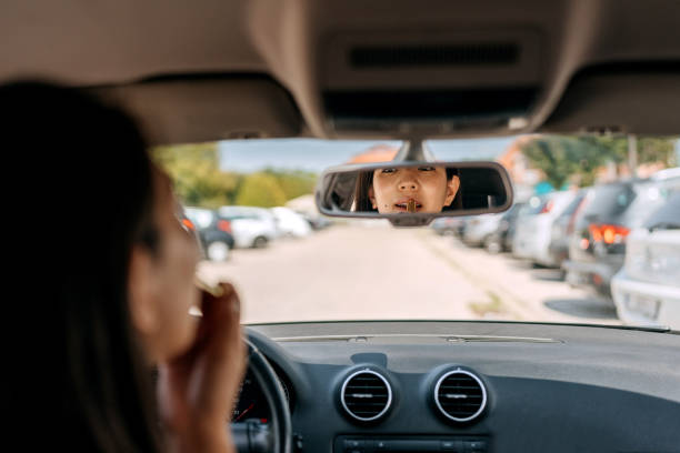 istock Woman applying lipstick in car 1633254896