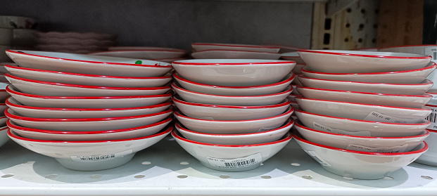 Several piles of plates neatly arranged on a shelf