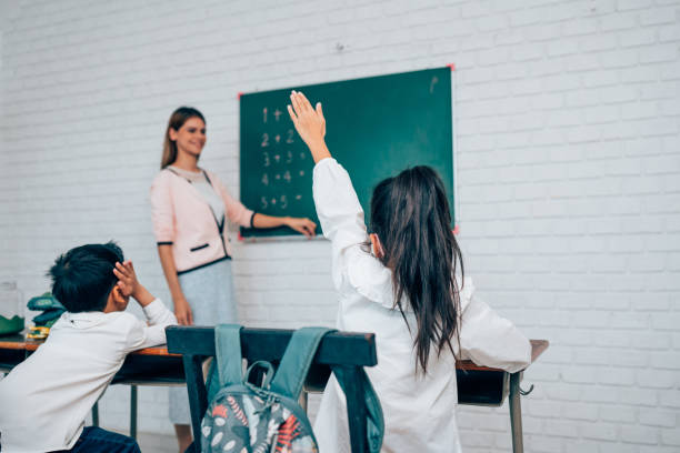 istock Little children raising hands up and having fun in class. 1633291479