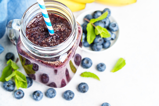 Blueberry banana smoothie in glass jar at white background. Close up.