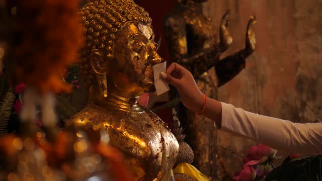 Man put the gold paste to the face of buddah statue