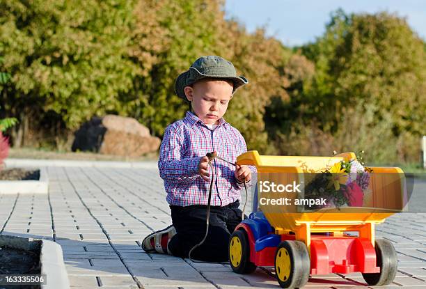 Linda Little Boy With Un Camión De Juguete Foto de stock y más banco de imágenes de Aire libre - Aire libre, Arrodillarse, Camión de juguete