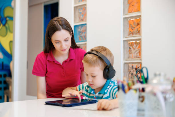 istock Boy wearing headphones at audiometry session, using tablet assisted by audiometrist 1633393416