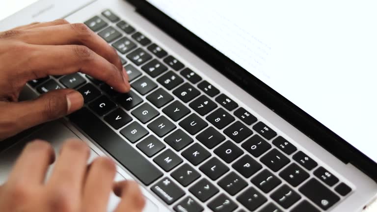 Close up view of a young businessman's busy hands working on a laptop or computer keyboard, sending emails, and surfing on a web browser