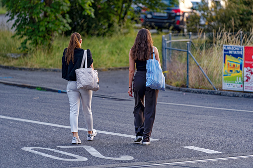Rear view of two young women crossing street at Swiss City of Lenzburg on a late spring evening. Photo taken June 7th, 2023, Lenzburg, Switzerland.