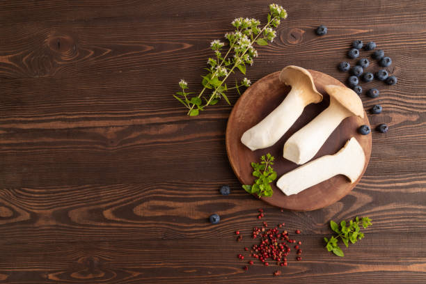 King Oyster mushrooms or Eringi (Pleurotus eryngii) on brown wooden. Top view, copy space.