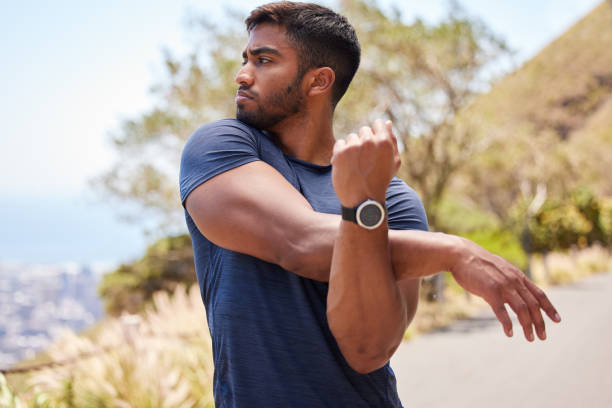 istock Thinking, man or runner stretching arms for fitness training, wellness or exercise outdoors on road. Relax, muscle flexibility and healthy Indian male athlete in warm up to start running workout 1633408091