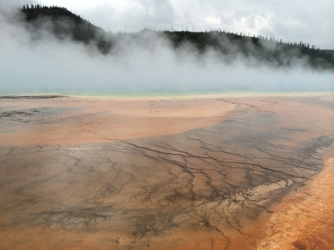 A stunning landscape of hot springs with billowing steam emanating from the body of water