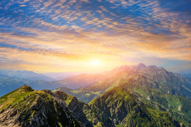 istock Panorama of a mountain range with alpine meadows during sunset with beautiful sky cloudscape. 1633431884