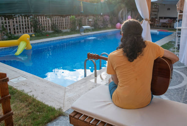 istock Young musician plays guitar in the pool 1633442657