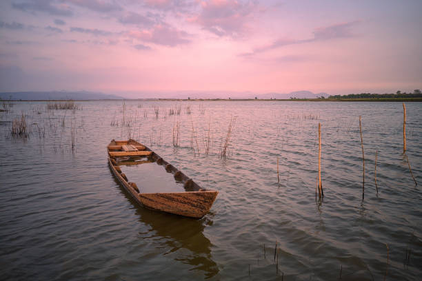A leaky wooden boat in the Gajah Mungkur reservoir at dusk.