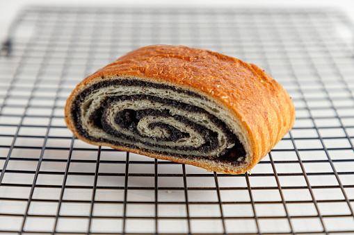 Piece of beautifully baked poppy seed roll on a serving grid