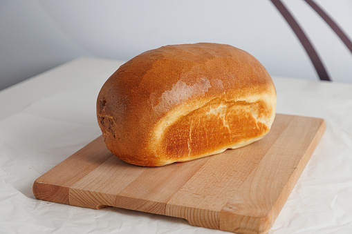 Beautifully baked bread with yellowish brown glazed crust, served on wooden board