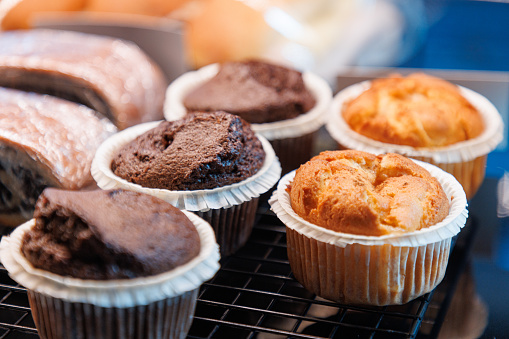 Close-up on beautifully baked muffins in wax paper cups on a grid in cafeteria