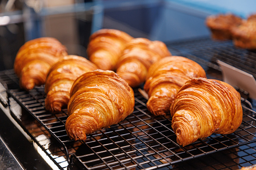 Close-up on beautifully baked golden crusty croissants on a grid in cafeteria