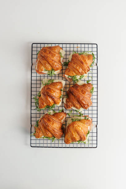 Directly above croissants filled with prosciutto, cheese and arugula on serving grid