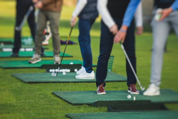 istock Group of golfers practicing and training golf swing on driving range practice, men playing on golf course, golf ball at golfing complex club resort 1633464103