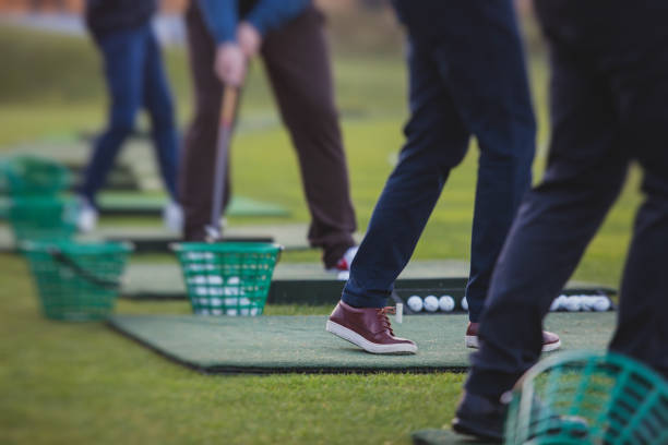 istock Group of golfers practicing and training golf swing on driving range practice, men playing on golf course, golf ball at golfing complex club resort 1633464106